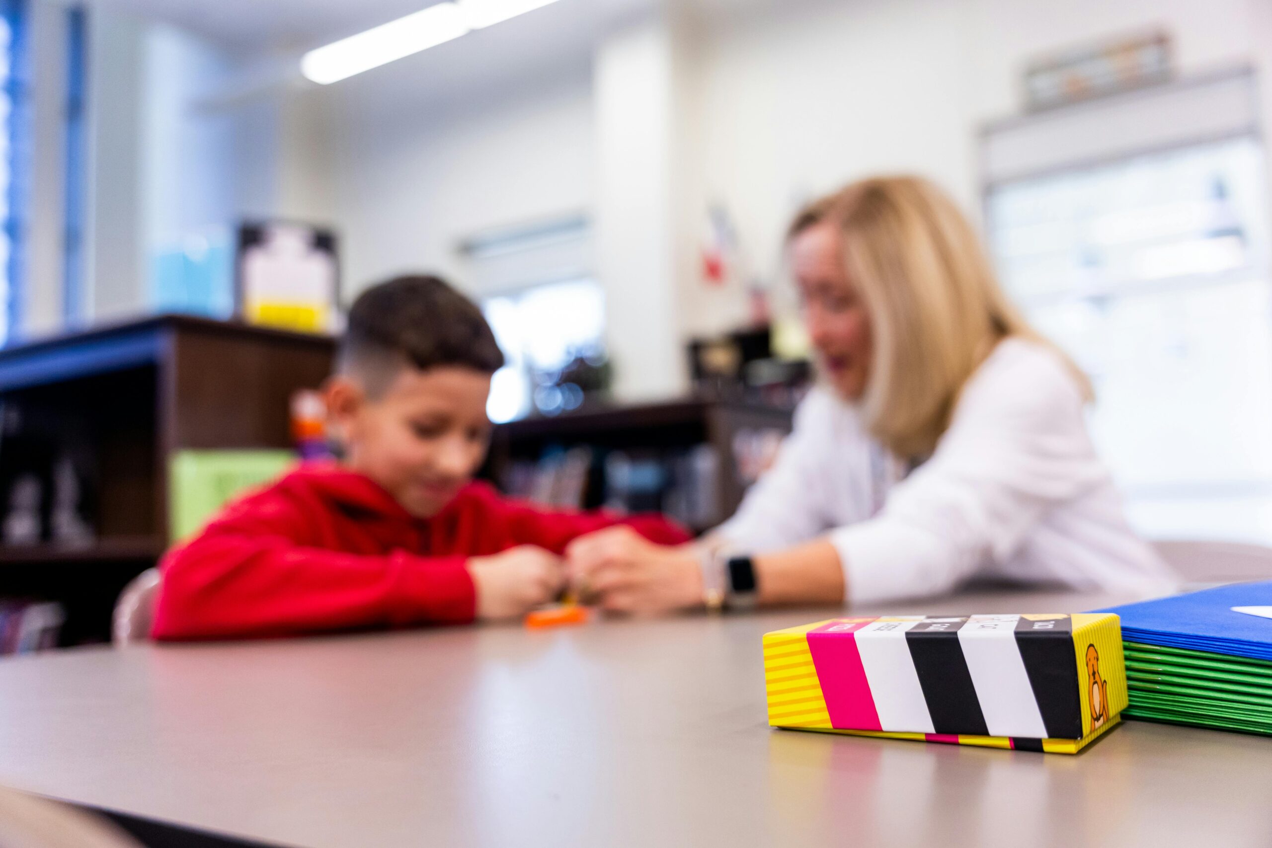 Focused classroom scene with a teacher and student engaged in learning activities.